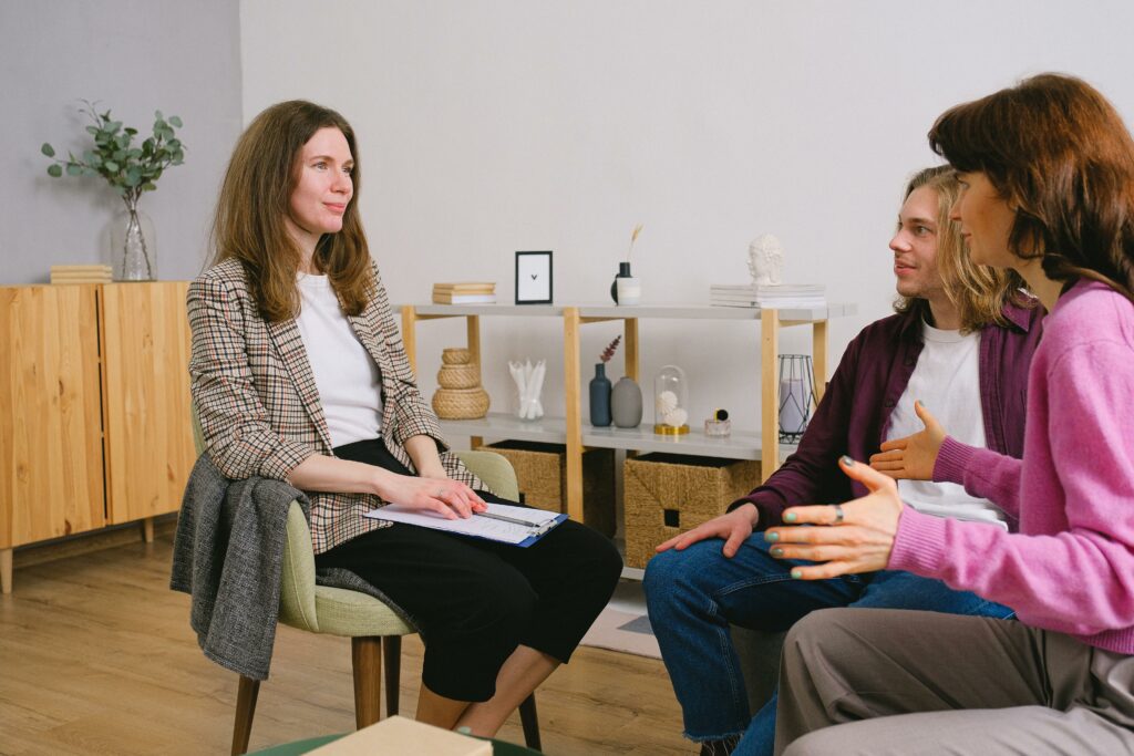 Young adults discuss with a counselor during an indoor therapy session.